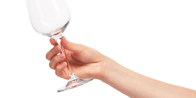 person holding empty wine glass while wondering does alcohol withdrawal cause insomnia