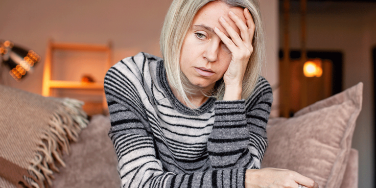 person sitting on couch with hand on head while struggling with effects of meth on the body