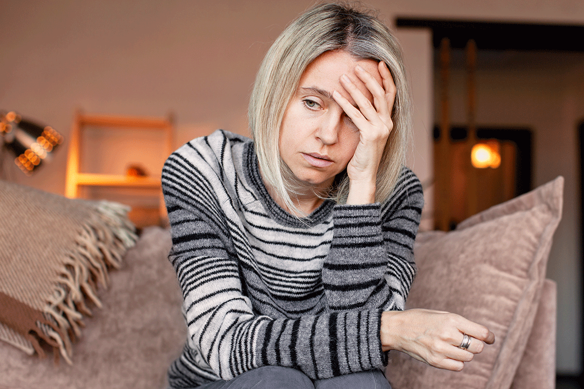 person sitting on couch with hand on head while struggling with effects of meth on the body