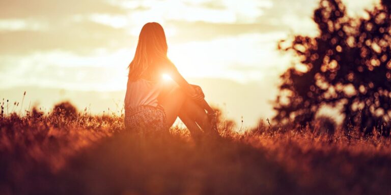 person sitting on hill watching sunset after reaping the benefits of a relapse program