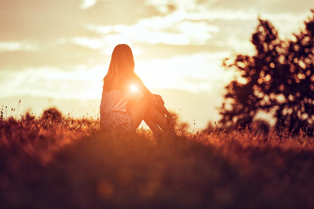 person sitting on hill watching sunset after reaping the benefits of a relapse program