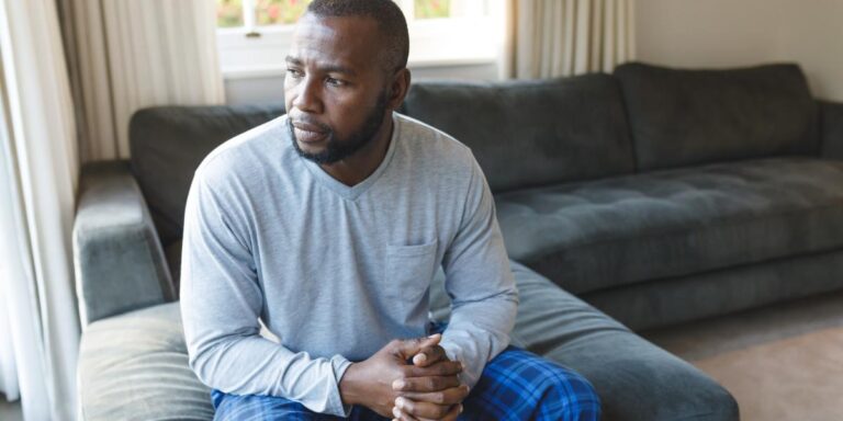 contemplative man sitting on couch wondering how mat can reduce opioid cravings