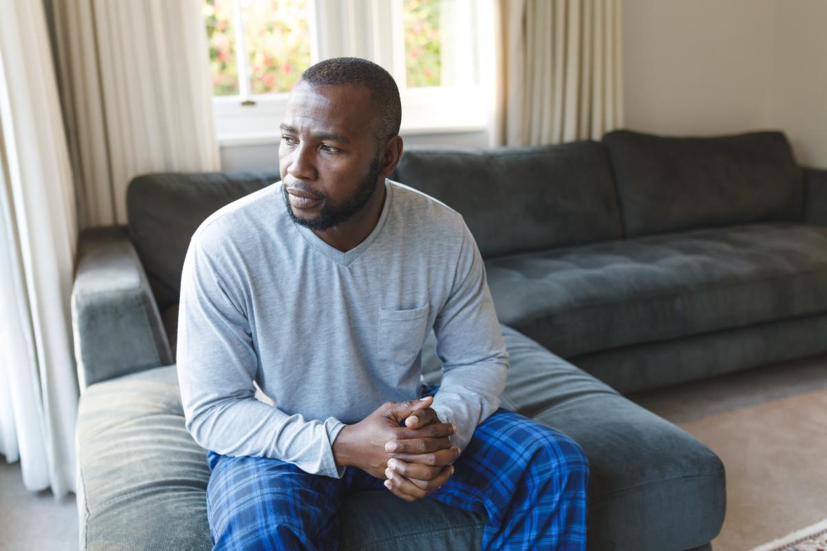 contemplative man sitting on couch wondering how mat can reduce opioid cravings